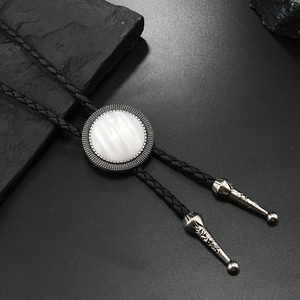 Detail of a vintage bolo tie with a white marble stone and engraved silver metal tips