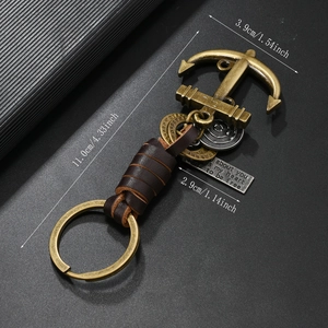 Macro shot of bronze anchor pendant and engraved tags on vintage leather keychain