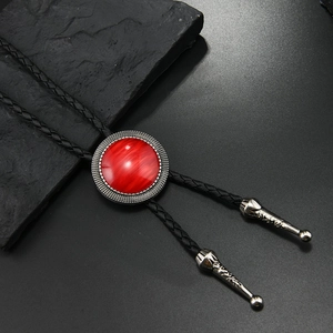 Detail of western bolo tie featuring a red cat eye stone and silver engraved metal frame