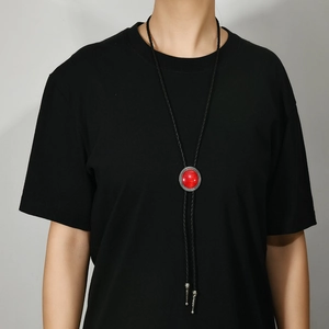 Retro bolo tie with large red oval gemstone and silver engraved metal detail on a black cord
