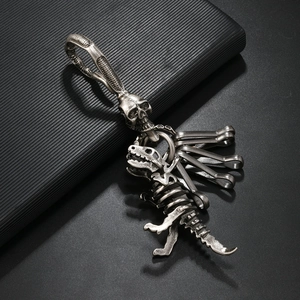 Macro shot of retro dinosaur skeleton pendant with skull spring hook on black background