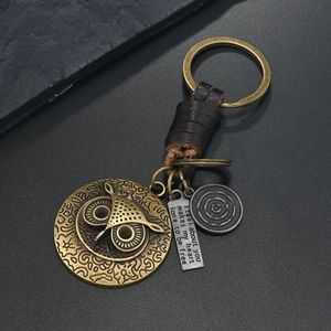 Vintage Eule Schlüsselanhänger mit Gravurplatte und geflochtenem Leder auf dunklem Stein