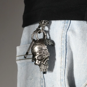 Gothic skull pendant metal keychain on blue jeans showing vintage punk style accessories