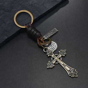 Detail of vintage braided leather keychain with cross pendant and engraved quote tag