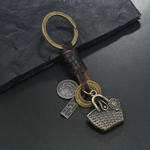 Detail of bronze alloy basket charm and woven leather keychain with engraved tag