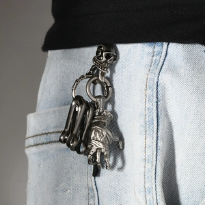 Porte-clés punk main de démon et crâne en argent vieilli accroché à un jean bleu