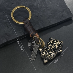Detail view of vintage bronze alloy kitten pendant on a hand-woven leather keychain