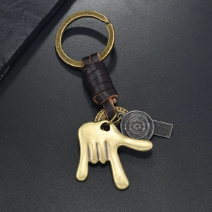 Retro bronze alloy keychain with leather strap and gesture pendant on dark background