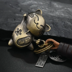 Retro bronze cat keychain with lucky cat charm and leather braided rope on dark stone