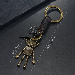 Détail d'un porte-clés robot en bronze vintage avec lanière en cuir tressé et étiquettes
