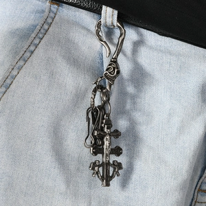 Retro silver alloy skeleton and Caravaca cross pendant keychain on blue jeans