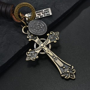Vintage braided leather keychain with gothic cross and engraved metal tags on dark stone