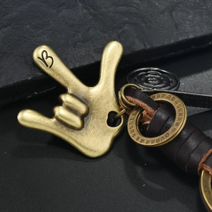 Macro shot of vintage bronze hand gesture charm with dark brown leather detailing