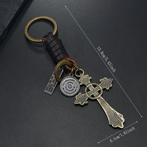 Detail view of retro braided leather keychain with bronze cross and engraved metal tags
