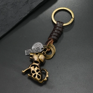 Vintage bronze dog keychain with leather wrap and engraved metal charm on dark surface