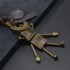 Porte-clés robot en bronze vintage avec lanière en cuir sur fond de pierre noire