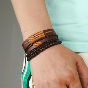 Detail of multi-layer leather bracelet with wooden beads and woven cords on a male wrist
