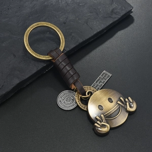 Portachiavi vintage in bronzo con pelle intrecciata e ciondoli in metallo con incisione