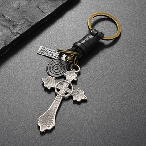 Close-up of vintage leather keychain with bronze cross pendant and engraved metal tags