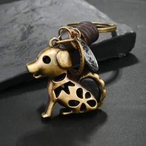 Retro bronze alloy puppy keychain with leather detail on black stone surface