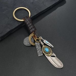 Detail of vintage leather keychain with bronze feathers, turquoise and engraved plate