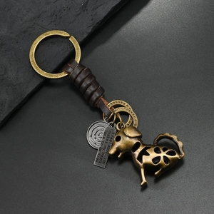 Detail of vintage bronze dog keychain with hollow floral patterns and leather wrap