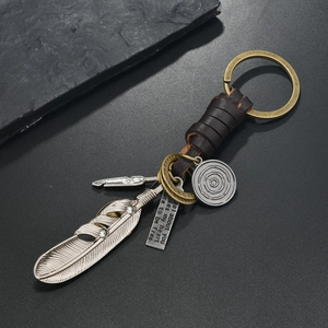 Close-up of vintage leather keychain with bronze feather charm and engraved quote tag