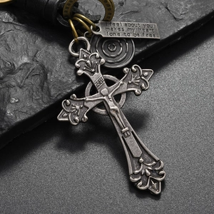 Detail of vintage crucifix pendant and engraved metal plate on black leather cord