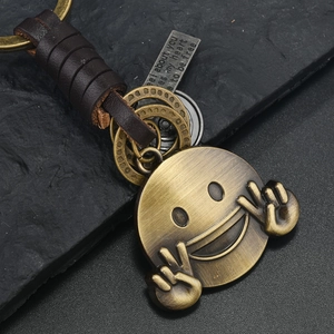 Portachiavi vintage in bronzo con faccina sorridente e cordino in pelle intrecciata