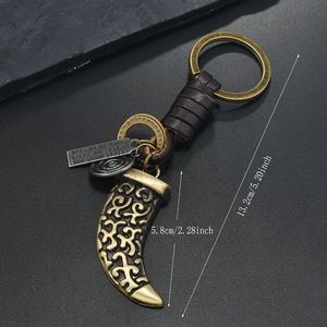 Detail of vintage bronze horn keychain with embossed patterns and woven leather strap