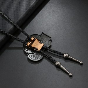 Detail van de bronzen bolo tie clip met reliëf letters op een zwart lederen koord