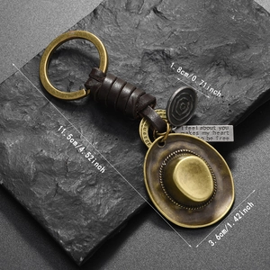 Detail of vintage cowboy hat keychain with braided leather rope and antique brass finish