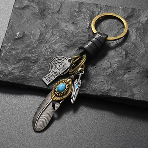 Close-up of vintage feather keychain with turquoise stone and engraved metal charm
