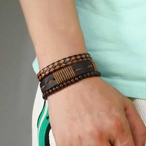 Detail view of multi-layer men's leather bracelet with woven bands and dark wooden beads