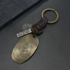 Detailed macro view of vintage bronze oval tag with spiral texture and brown leather strap