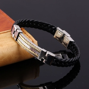 Close-up of a men's black leather bracelet with steel wire inlay on a brown notebook