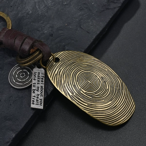 Macro detail of retro bronze alloy keychain with woven leather and engraved silver tags