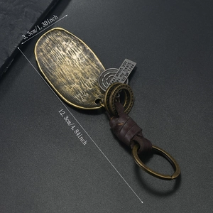 Detail of vintage bronze ginkgo leaf keychain with leather strap and engraved metal tag