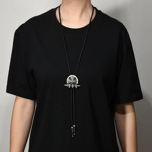 Detail van vintage zilveren bolo tie met kruis en schedels aan gevlochten PU koord