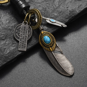Vintage leather keychain with silver feathers and blue turquoise on a dark stone background