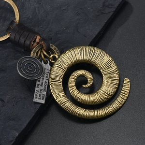 Detail of vintage bronze spiral disc keychain with braided leather and engraved metal tag