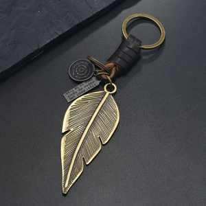 Close-up of vintage bronze alloy feather keychain with leather wrap and engraved plate