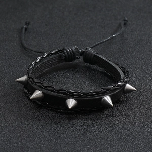 Détail du bracelet en cuir noir avec rivets argentés et cordon de serrage réglable