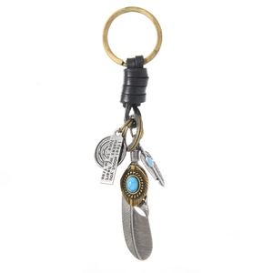 Vintage bronze keychain with turquoise feathers and engraved leather strap on white background
