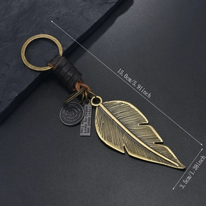 Macro view of vintage bronze feather keychain with leather wrap and size measurements