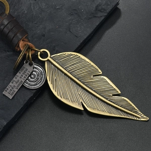 Detail of vintage bronze feather pendant and dark brown braided leather keychain