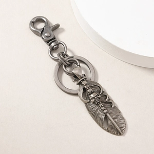 Detailed close-up of antique silver skull and feather pendant on a metal keychain