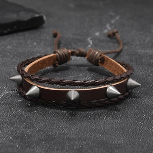 Détail d'un bracelet punk en cuir marron avec rivets en métal argenté et tressage