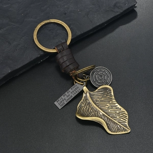 Macro detail of bronze ginkgo leaf and leather keychain with engraved vintage charm