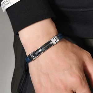Macro shot of a men's woven bracelet with a steel plate and black cable inlay detail